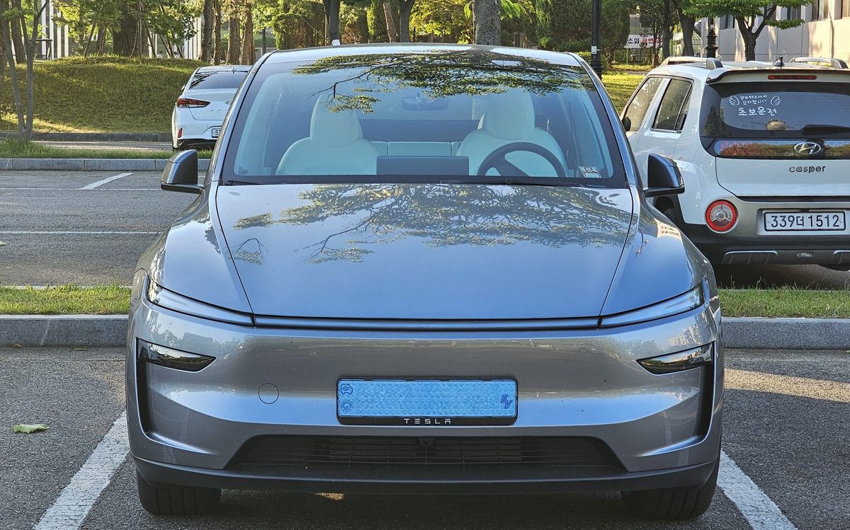 New Tesla Model Y in Quicksilver, seen from the front in a parking lot